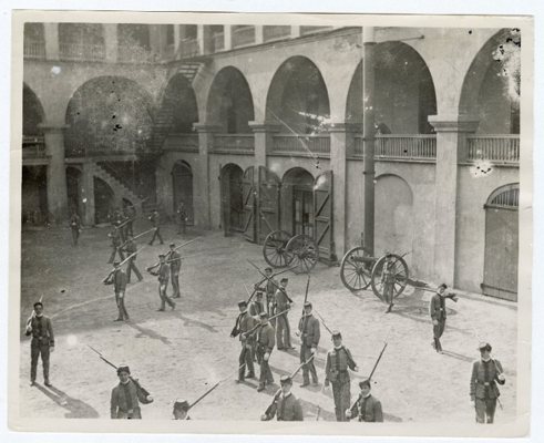 Cadets with shouldered rifles marching in the arcaded courtyard of the original Citadel, two field guns parked beside the archways
